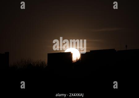 Il sole tramonta dietro i grandi condomini Foto Stock