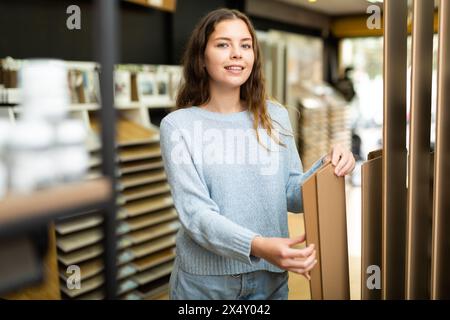 Cliente femmina che tiene campioni di pannelli di legno nel negozio di ferramenta Foto Stock