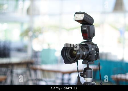 Fotocamera DSLR Canon nera montata su un cavalletto con flash esterno pronto all'uso Foto Stock
