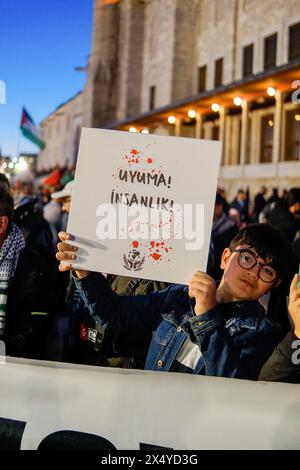 Istanbul, Turchia. 5 maggio 2024. Un ragazzo ha un cartello che dice "non dormire umanità" durante la marcia. Centinaia di persone hanno marciato a Istanbul la sera del 5 maggio per esprimere la loro solidarietà al popolo palestinese. I manifestanti hanno condannato gli attacchi israeliani e hanno chiesto un cessate il fuoco immediato e l'accesso agli aiuti umanitari. La marcia ha fatto eco alle richieste globali di pace nella regione. Credito: SOPA Images Limited/Alamy Live News Foto Stock