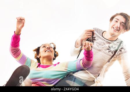 Esuberante giovane coppia a metà salto, sorridente e vestita coloratamente in una festa vivace Foto Stock