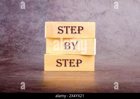 Testo concept Step by Step scritto su blocchi di legno su sfondo scuro Foto Stock