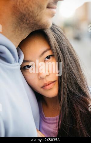 Primo piano ritratto di una giovane bella donna asiatica che abbraccia il suo ragazzo. Foto Stock