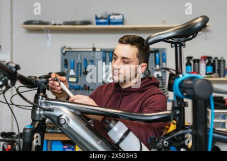 Il meccanico utilizza una chiave a cricchetto Allen sul manubrio di una mountain bike elettrica. Foto Stock