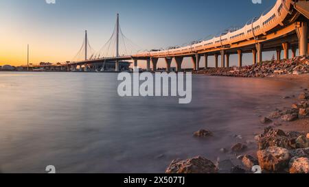 Lo splendido tramonto illumina un moderno ponte strallato, catturato sulle acque calme. Il diametro occidentale ad alta velocità a San Pietroburgo. Foto Stock