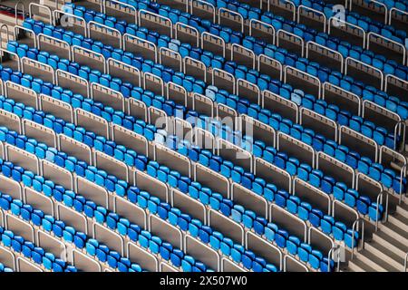 I sedili dello stadio blu e bianchi sono disposti in diagonale, mostrando un contrasto e una struttura visivamente sorprendenti in uno stadio vuoto. Foto Stock