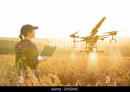 Donna coltivatore controlla drone irroratrice con un tablet. Agricoltura intelligente e agricoltura di precisione Foto Stock