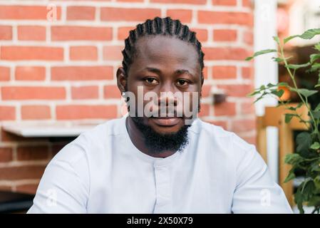 Allegro abito turistico maschile in bianco indossa un sorriso etnico dashiki al City Street Cafe. Il modello di viaggio afroamericano ha tempo libero Foto Stock