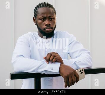 Allegro abito turistico maschile in bianco indossa un sorriso etnico dashiki al City Street Cafe. Il modello di viaggio afroamericano ha tempo libero Foto Stock