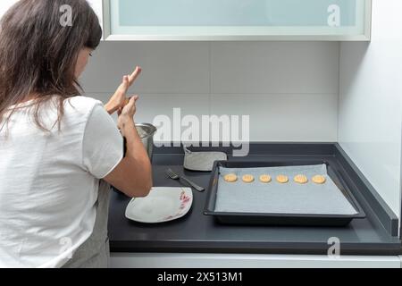 individuale in cucina, preparando biscotti su una teglia da forno, con un'estetica moderna e privacy Foto Stock