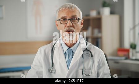 Visita medica POV online del medico: Il medico di mezza età sta effettuando una videochiamata con un paziente. Senior Health Care Professional dare consigli, spiegare i risultati del test. Ripresa Point of View Foto Stock