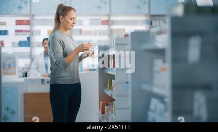 Farmacia farmacia: Bella giovane donna caucasica sceglie di acquistare Medicina, farmaci, vitamine, Searches scaffali per la scelta migliore. Moderni scaffali Pharma Store con prodotti per la salute e la bellezza Foto Stock