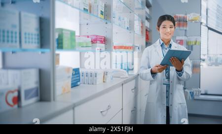 Farmacia Drugstore: Bella farmacista asiatica utilizza computer tablet digitale, fa inventario Checkup, prescrizione online di pacchetti di medicina, farmaci, scatole di vitamina, integratori, prodotti sanitari Foto Stock