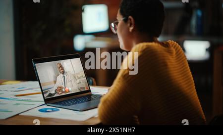 Il bellissimo multietnico Latina Manager sta effettuando una videochiamata al suo medico su un laptop in un ambiente ufficio creativo. L'uomo sta parlando con il suo consulente medico su una telecamera dal vivo, chiedendo di salute. Foto Stock