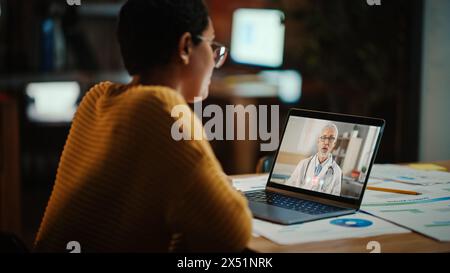 Il bellissimo multietnico Latina Manager sta effettuando una videochiamata al suo medico su un laptop in un ambiente ufficio creativo. L'uomo sta parlando con il suo consulente medico su una telecamera dal vivo, chiedendo di salute. Foto Stock