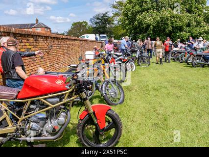 Earsham, Norfolk, Regno Unito – 5 maggio 2024. Appassionati di motociclette che guardano intorno alle motociclette in mostra in una piccola mostra di motociclette Foto Stock