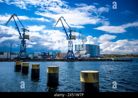 Wismar, Germania. 22 aprile 2024. Le gru per cantieri navali si trovano sul cantiere navale di fronte al salone di costruzione navale dell’ex cantiere navale MV. ThyssenKrupp Marine Systems (TKMS) ha acquisito il cantiere navale di Meclemburgo-Vorpommern dalla proprietà fallimentare del gruppo MV-Werften, che è fallita all’inizio del 2022. Crediti: Jens Büttner/dpa/Alamy Live News Foto Stock