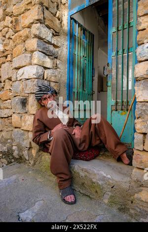 Uraman Takht, Iran - 15 aprile 2024: Ritratto di un uomo seduto in una strada a Uraman Takht nel Kurdistan, Iran. Foto Stock
