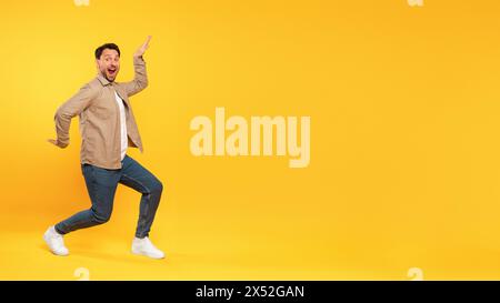 Uomo in giacca Tan che balla su sfondo giallo Foto Stock