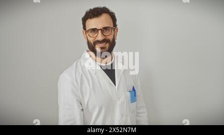 Uomo con barba sorridente in camice bianco da laboratorio con occhiali isolati su sfondo bianco. Foto Stock