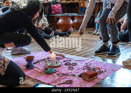 Donne che mettono oggetti intorno a una candela su una coperta per una cerimonia d'intenti. Foto di alta qualità Foto Stock