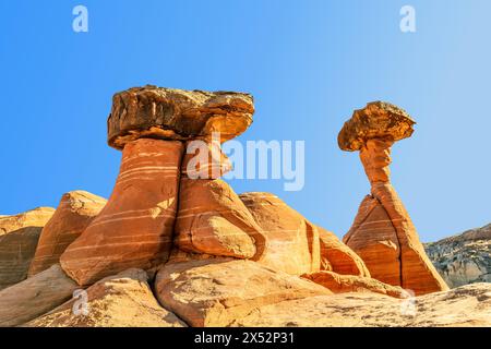 Lo hoodoo in pietra arenaria bianca e rossa a Kanab Utah mostra guglie altamente erose e rocce più dure bilanciate sulla parte superiore incorniciate da un cielo blu. Foto Stock