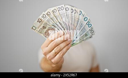 Bell'uomo barbuto che tiene in mano un fan delle banconote zloty polacche su sfondo bianco, simboleggiando ricchezza e risparmio. Foto Stock