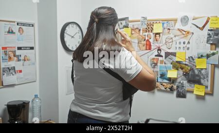 Donna ispanica al telefono di fronte al Consiglio del crimine all'ufficio investigativo Foto Stock