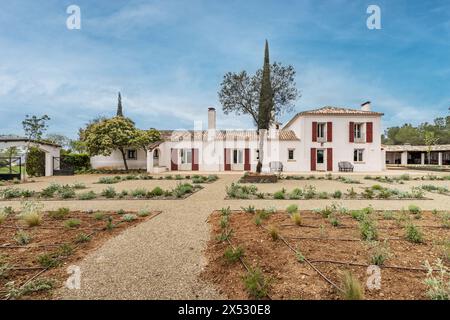 Una casa colonica in stile andaluso con facciate bianche e persiane rosse in legno e giardini piantati di recente Foto Stock