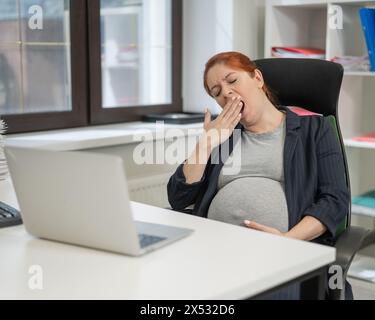 Donna incinta che dorme alla sua scrivania in ufficio. Foto Stock