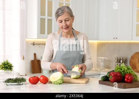 Una casalinga felice che taglia il cavolo a tavola in cucina Foto Stock