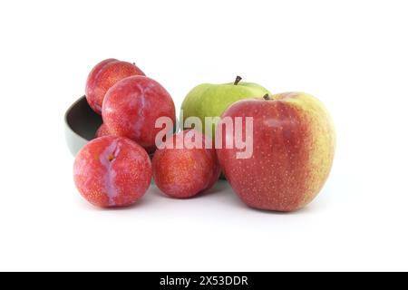 Assortimento di frutta fresca sullo sfondo bianco, tra cui mele verdi vivaci e prugne cremisi Foto Stock