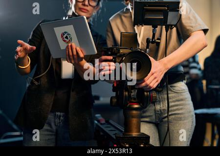 Vista font ripresa ritagliata di due donne che gestiscono una videocamera professionale che lavora nella troupe cinematografica sul set Foto Stock