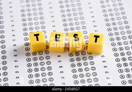 Carta per l'esame con la parola test scritta su cubi gialli. Concetti di istruzione, esame, quiz e successo scolastico. Foto Stock