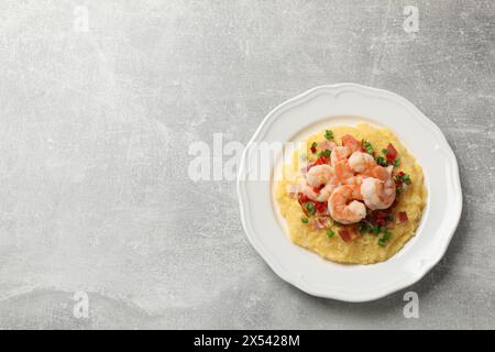 Piatto con gustosi gamberetti freschi, pancetta, fiocchi d'avena, cipolla verde e pepe su un tavolo testurizzato grigio, vista dall'alto. Spazio per il testo Foto Stock