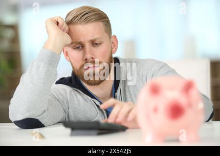 giovane con un salvadanaio isolato sul bianco Foto Stock