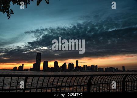 Lo skyline di Jersey City sotto gli splendidi cieli del tramonto, visto da Battery Park - Manhattan, New York City Foto Stock