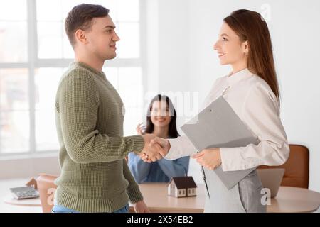 Agente immobiliare con compratore che stringe la mano in ufficio Foto Stock