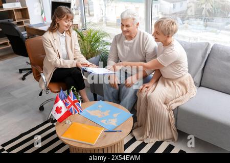 Agente di viaggio donna che fornisce domanda di visto per coppie mature in ufficio Foto Stock