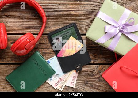 Composizione con carta di credito nera, regalo, cuffie e denaro su sfondo in legno Foto Stock