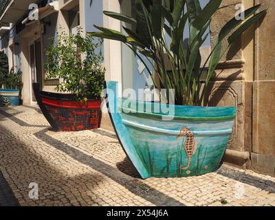 Grandi fioriere decorative dipinte a mano a forma di barca nel centro di Olhão nel sud del Portogallo, che celebrano il forte patrimonio di pesca di questa piccola città Foto Stock