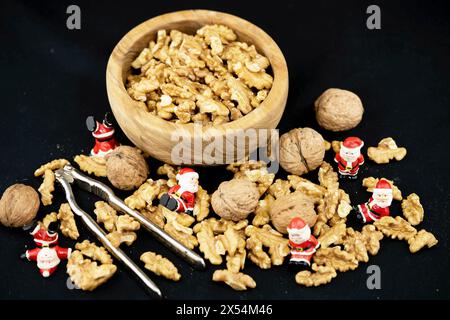 noce (Juglans regia), noci con schiaccianoci, ciotola di legno e monete natalizie Foto Stock