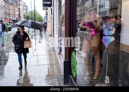 La pioggia del lunedì festivo non scoraggia i molti acquirenti e visitatori in Oxford Street che sfidano il maltempo passando Ann Summers il 6 maggio 2024 a Londra, Regno Unito. Oxford Street è un importante centro commerciale nel West End della capitale ed è la strada commerciale più trafficata d'Europa, con circa mezzo milione di visitatori al giorno ai suoi circa 300 negozi, la maggior parte dei quali sono negozi di moda e di abbigliamento di alta moda. Foto Stock