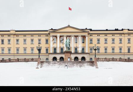 Facciata del palazzo reale neoclassico di Oslo in inverno con volo standard reale norvegese e statua equestre del re Carl Johan, Oslo, Norvegia Foto Stock