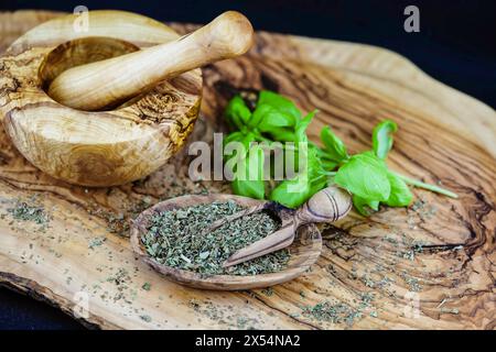 Basilico dolce (Ocimum basilicum), foglie di basilico, fresco ed essiccato su un piatto di legno con Malta Foto Stock