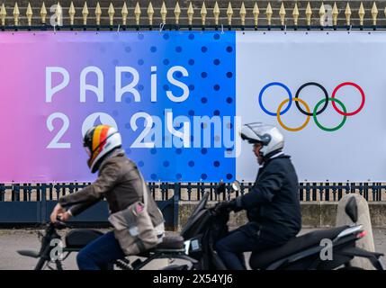 06 maggio 2024, Francia, Parigi: Gli anelli olimpici e le parole Parigi 2024 possono essere visti su uno striscione all'Assemblea Nazionale. Le Olimpiadi e le Paralimpiadi si svolgeranno in Francia quest'estate. Foto: Robert Michael/dpa Foto Stock