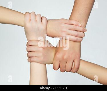 Gruppo di bambini che si aggrappano l'un l'altro, simboleggiando il lavoro in squadra e l'unità su sfondo grigio isolato. Foto Stock