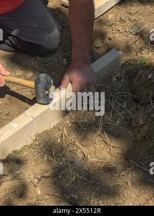 Impostazione di restrizioni di bordo acquistare mettendo cordolo di confine pietre in massa di calcestruzzo umido Foto Stock