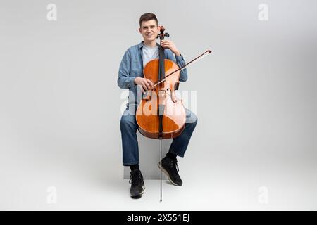 Giovane uomo che indossa abbigliamento casual che gioca a violoncello Foto Stock