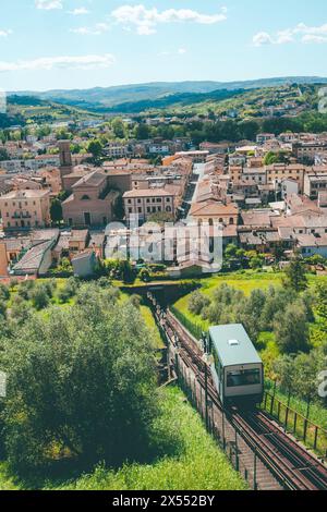 La pittoresca funicolare che sale sulla collina fino al centro storico di Certaldo in Toscana, in una giornata di sole con cielo azzurro e nuvole. Foto Stock